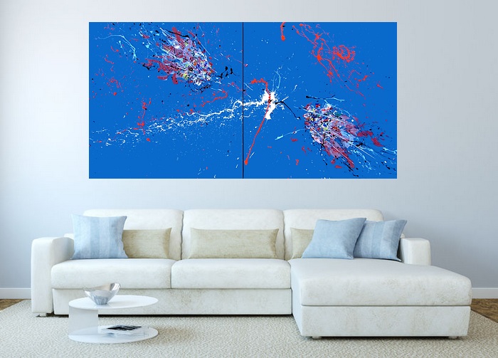 I QUADRI ASTRATTI DI GOA IN UNA SALA MODERNA CON DIVANO IN PELLE SCAMOSCIATA GRIGIO CHIARO, TAVOLINO IN VETRO ROTONDO SATINATO, TAPPETO ECRU E CUSCINI DI COLORE AZZURRO