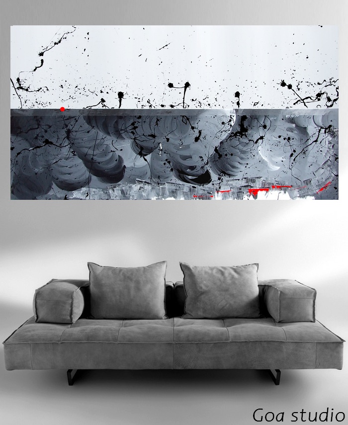 Un quadro su tela firmato pittore Goa, posizionato su di una parete grigia sopra ad un divano in pelle di alcantara color grigio. Il pavimento della sala è realizzato in grandi blocchi di cemento spazzolato lucido